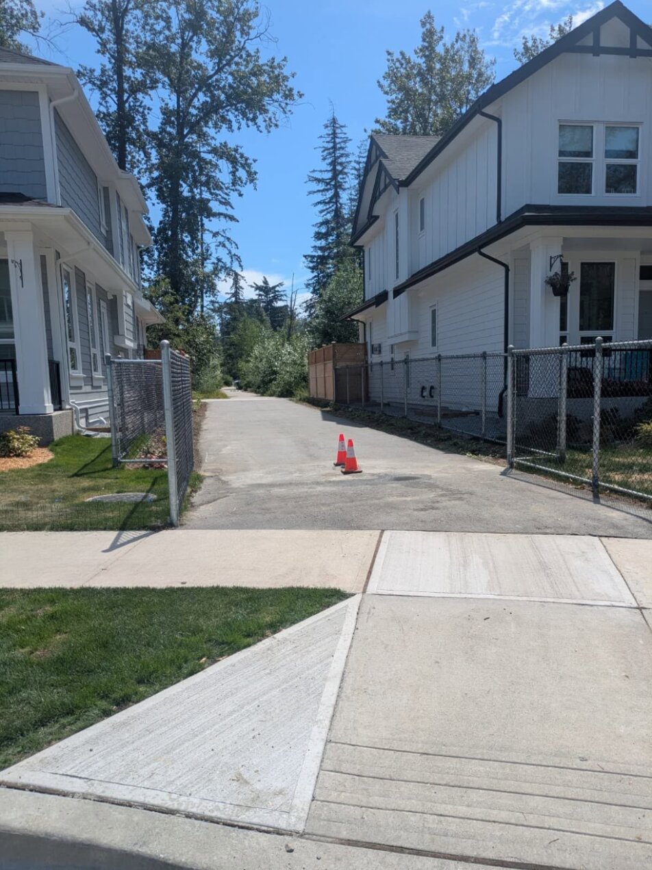 A Parry Evans Trail entrance at a residential street with the maze gate removed, leaving an open paved path marked by two traffic cones