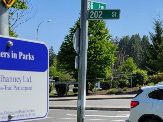 The 86 Ave and 202 St street sign at the crossing